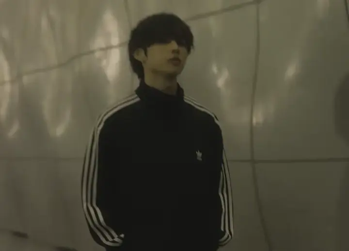 타일 복도에 서 있는 트랙 재킷 차림의 선우