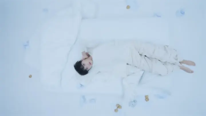 흰 공간에 누워 있는 인물과 주변 오브제
