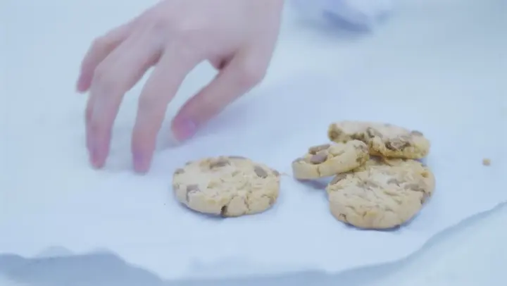흰 바닥 위 쿠키를 향해 뻗은 손